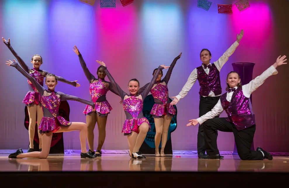 Studio 8 Dance students performing a recital number on stage under coloured lights