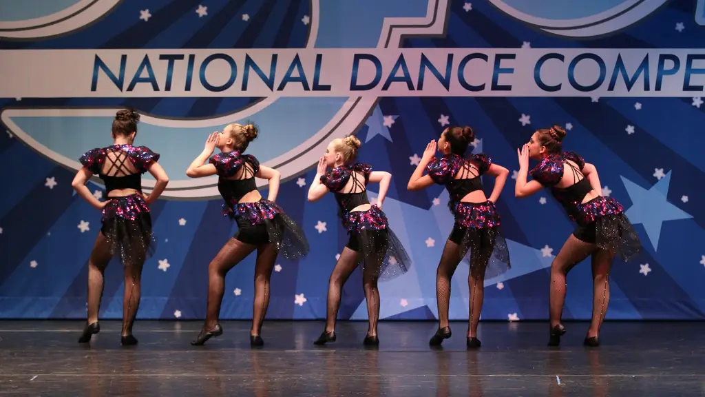 Five Studio 8 dancers in black sequin competition costumes in front of a national dance competition backdrop